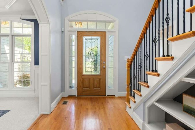 Une porte en bois avec un escalier classique pour créer une entrée accueillante et lumineuse.
